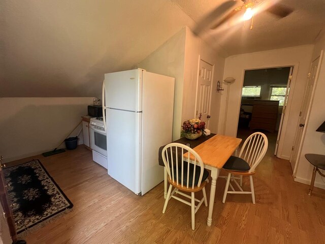 kitchen featuring white appliances, a ceiling fan, vaulted ceiling, and light wood-style floors