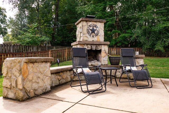 view of patio featuring an outdoor stone fireplace and fence