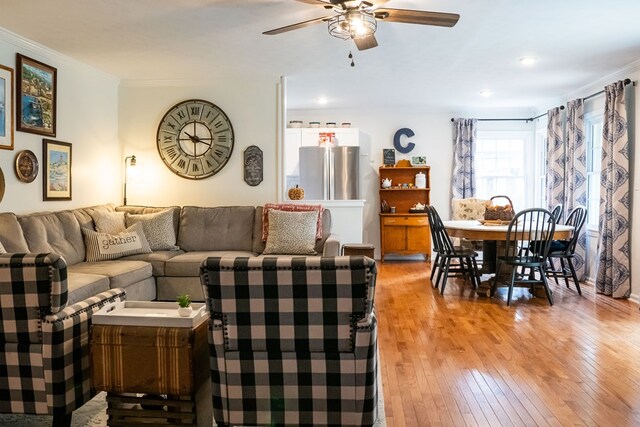 living area with a ceiling fan, light wood-type flooring, and crown molding