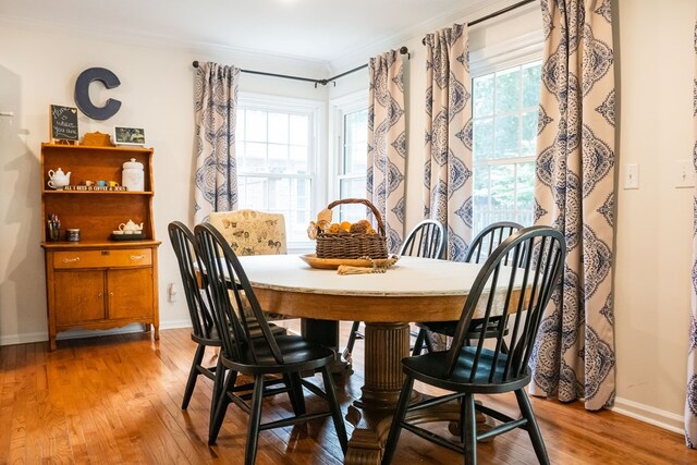 dining area featuring ornamental molding, baseboards, and wood finished floors