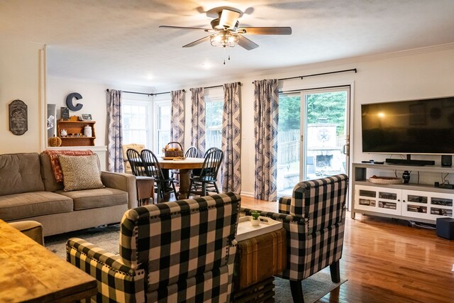 living area featuring a ceiling fan, crown molding, and wood finished floors