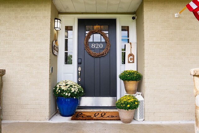 view of exterior entry featuring brick siding