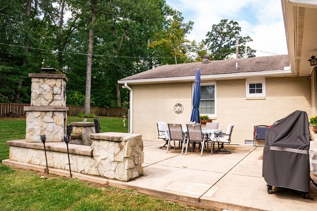 view of patio / terrace with a fireplace, fence, and outdoor dining space