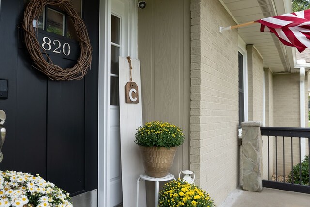 doorway to property featuring a porch and brick siding