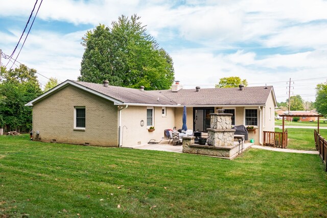 back of house featuring a patio, brick siding, an outdoor stone fireplace, crawl space, and a lawn