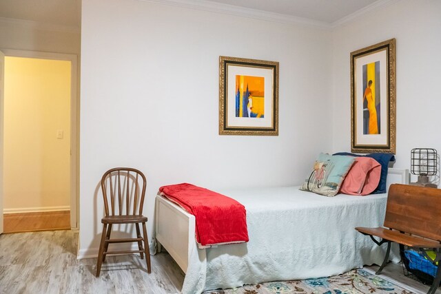 bedroom with light wood-style floors, ornamental molding, and baseboards