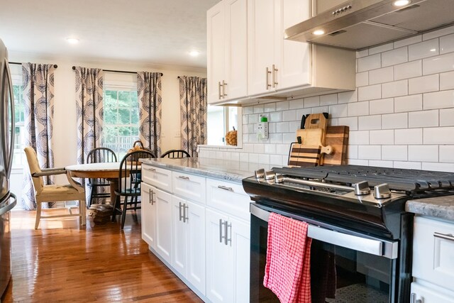 kitchen featuring under cabinet range hood, stainless steel range with gas cooktop, white cabinets, and dark wood-style flooring