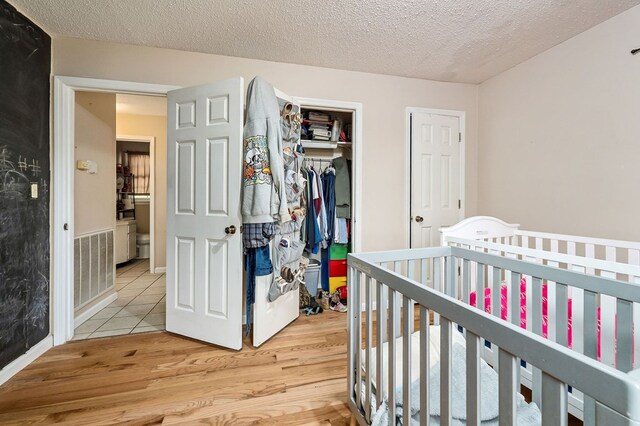 bedroom with light wood finished floors, a textured ceiling, and a closet