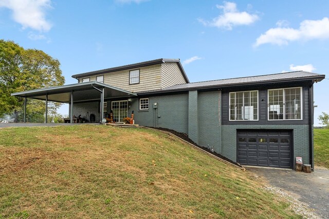 back of property featuring a yard, aphalt driveway, an attached garage, and brick siding