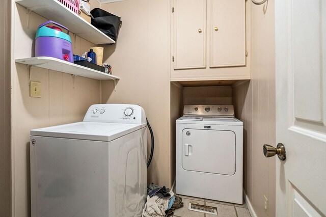 laundry area featuring light tile patterned floors, washing machine and dryer, and cabinet space