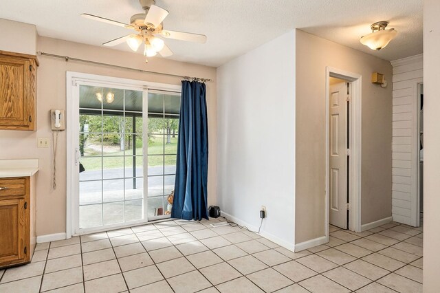 spare room featuring ceiling fan, baseboards, a textured ceiling, and light tile patterned flooring