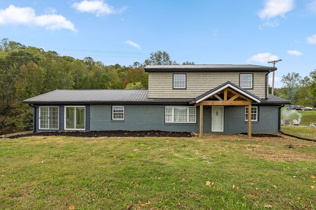 traditional-style home featuring metal roof, a front lawn, and brick siding