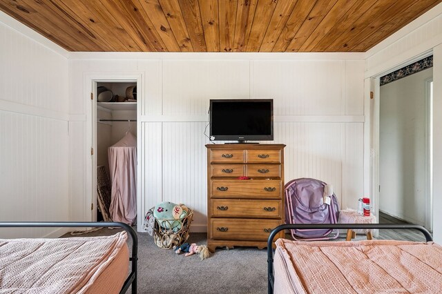 carpeted bedroom featuring wooden ceiling and a decorative wall