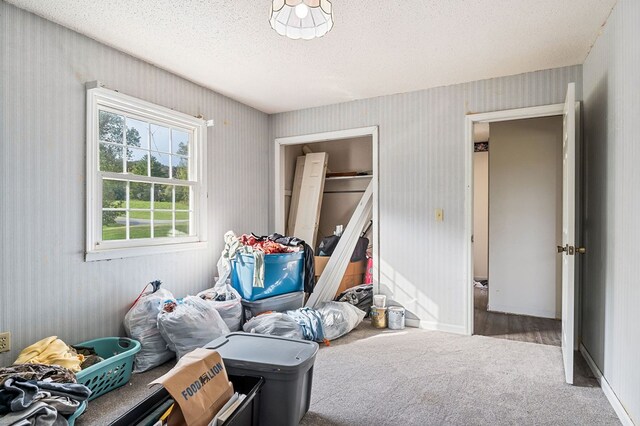 bedroom with wallpapered walls, carpet, baseboards, and a textured ceiling