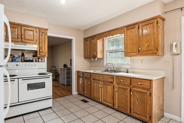 kitchen with brown cabinets, light countertops, under cabinet range hood, double oven range, and a sink