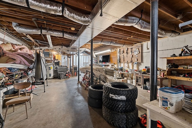 unfinished basement featuring concrete block wall, water heater, and a workshop area