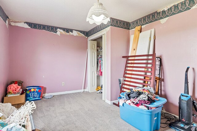 interior space with a textured ceiling, a chandelier, carpet flooring, and baseboards