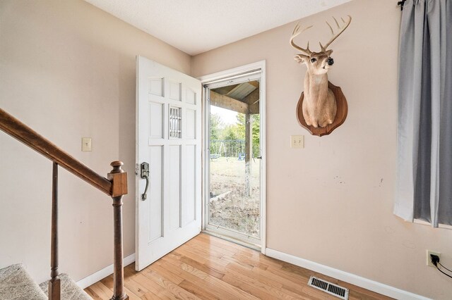 entrance foyer with visible vents, light wood-style flooring, baseboards, and stairs