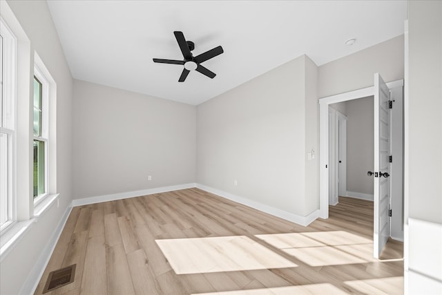 unfurnished room featuring a ceiling fan, light wood-style flooring, visible vents, and baseboards