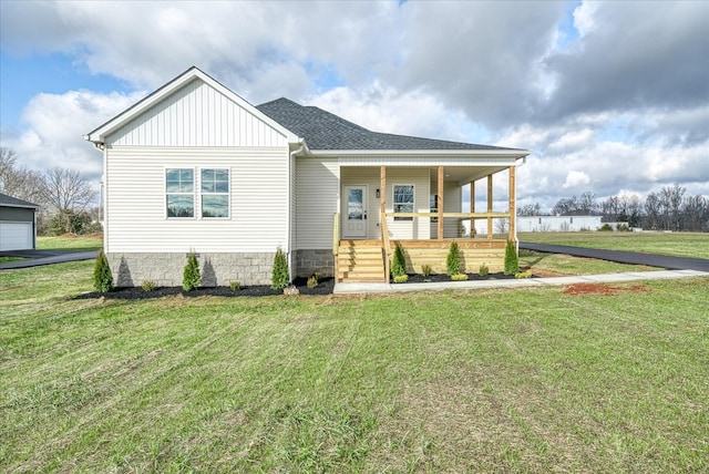 view of front of property with covered porch, a shingled roof, board and batten siding, and a front yard