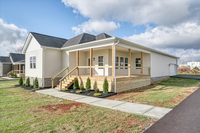 view of front of home with covered porch, a shingled roof, and a front yard