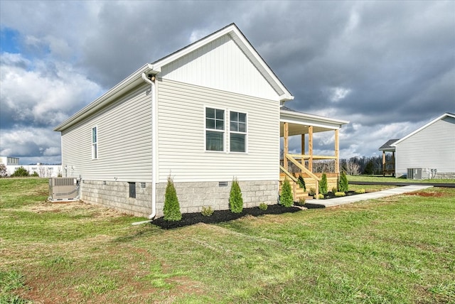 view of side of property with crawl space, central AC unit, and a lawn