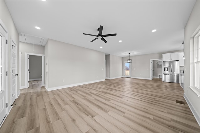 unfurnished living room with recessed lighting, visible vents, attic access, light wood-style floors, and baseboards