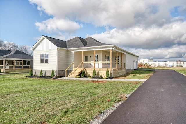 view of front of home with covered porch, roof with shingles, and a front lawn