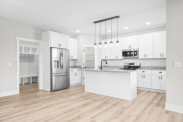 kitchen featuring appliances with stainless steel finishes, a kitchen island with sink, pendant lighting, and white cabinets