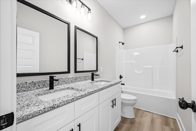 full bath with shower / bath combination, toilet, a sink, and wood finished floors