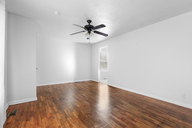 spare room featuring baseboards, dark wood-type flooring, visible vents, and a ceiling fan