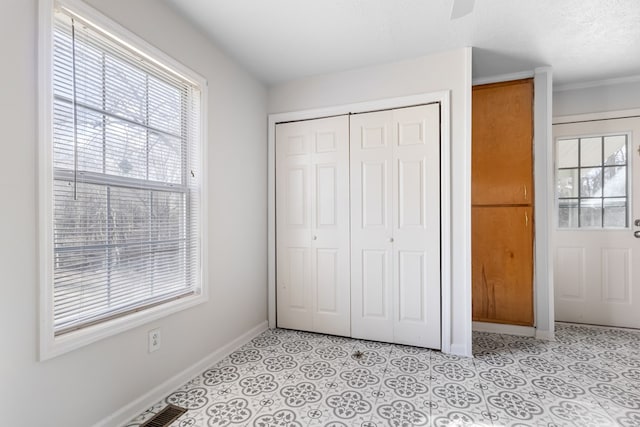 unfurnished bedroom featuring multiple windows, baseboards, a closet, and light tile patterned flooring