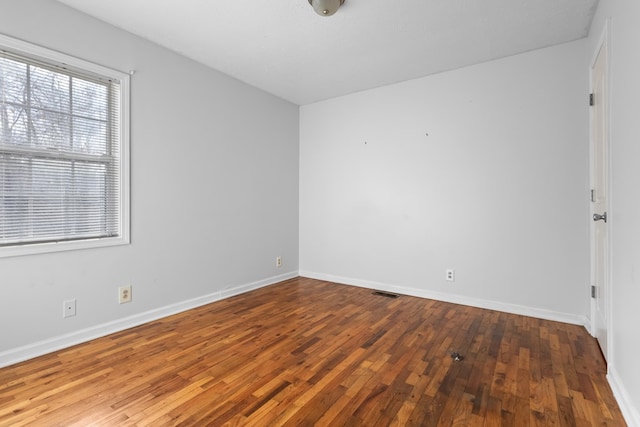 unfurnished room with visible vents, baseboards, and wood finished floors