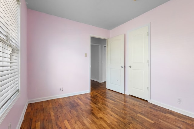 unfurnished bedroom with dark wood finished floors and baseboards