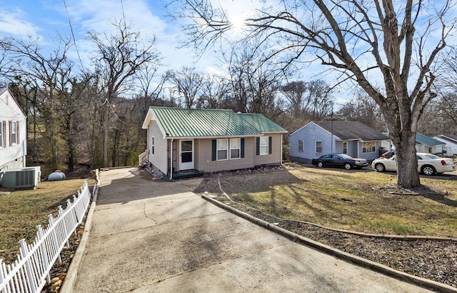 single story home with metal roof, cooling unit, fence, concrete driveway, and a front lawn