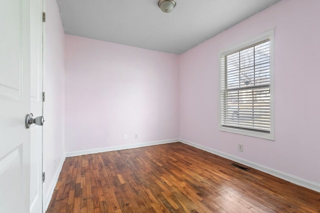 spare room featuring baseboards, visible vents, and wood finished floors