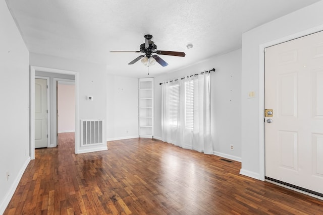 interior space featuring a textured ceiling, visible vents, and dark wood-style flooring