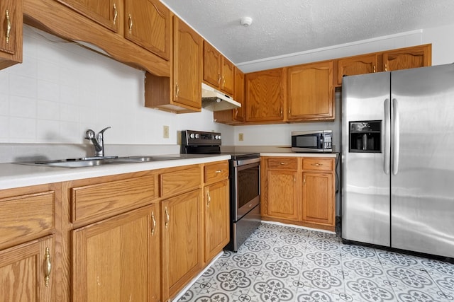 kitchen with brown cabinets, stainless steel appliances, light countertops, under cabinet range hood, and a sink