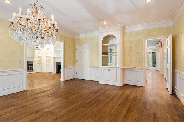 unfurnished dining area with a fireplace, ornamental molding, a decorative wall, and wood finished floors