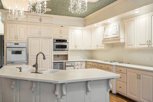 kitchen featuring light countertops, white appliances, a kitchen island with sink, and an inviting chandelier