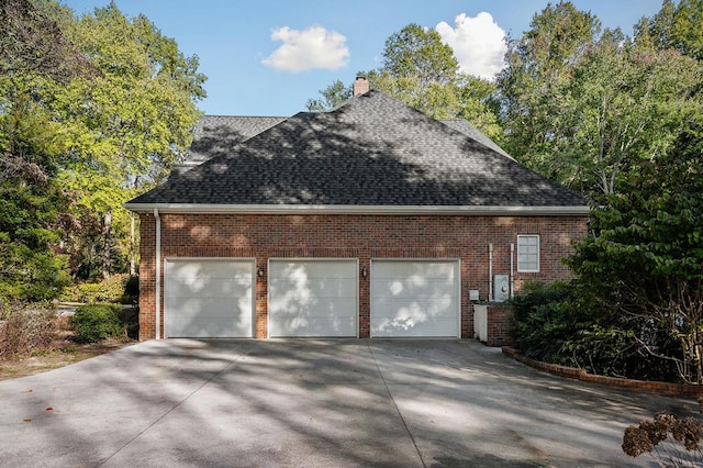 view of side of property with a shingled roof, brick siding, and a chimney