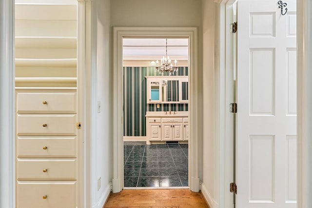 hallway with a chandelier, light wood-type flooring, and baseboards