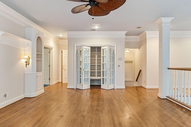 empty room featuring light wood-type flooring, ornate columns, baseboards, and ornamental molding