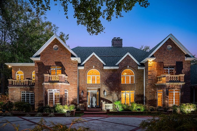 traditional-style home featuring brick siding, a chimney, and roof with shingles