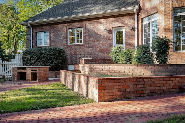 view of home's exterior featuring brick siding, fence, and roof with shingles