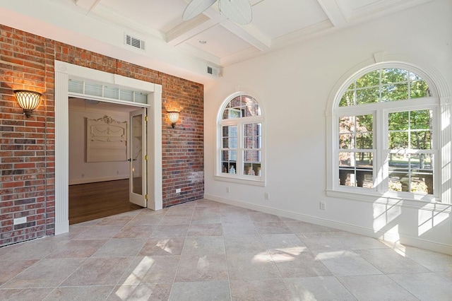 spare room with brick wall, plenty of natural light, coffered ceiling, and visible vents