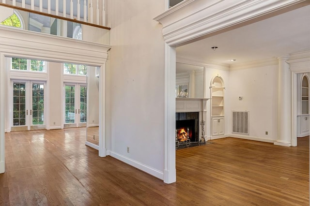 unfurnished living room with french doors, a fireplace, wood finished floors, and visible vents