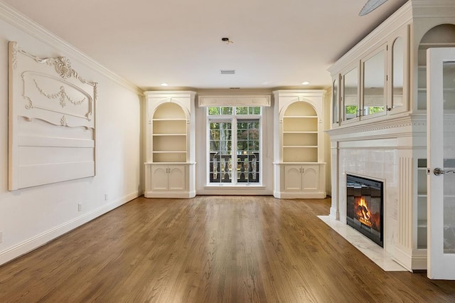 unfurnished living room featuring baseboards, a tile fireplace, ornamental molding, wood finished floors, and recessed lighting