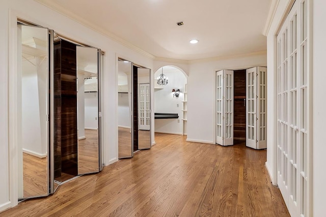 interior space with arched walkways, wood finished floors, baseboards, french doors, and crown molding