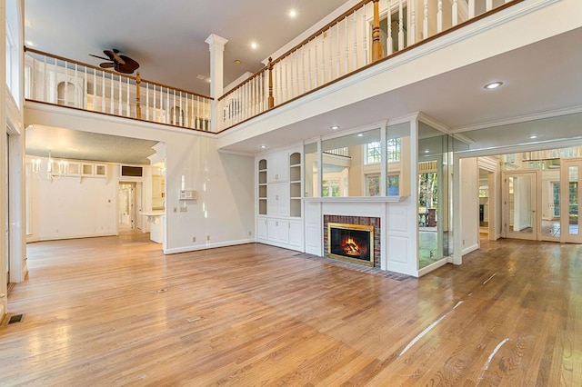 unfurnished living room featuring a ceiling fan, a brick fireplace, plenty of natural light, and wood finished floors